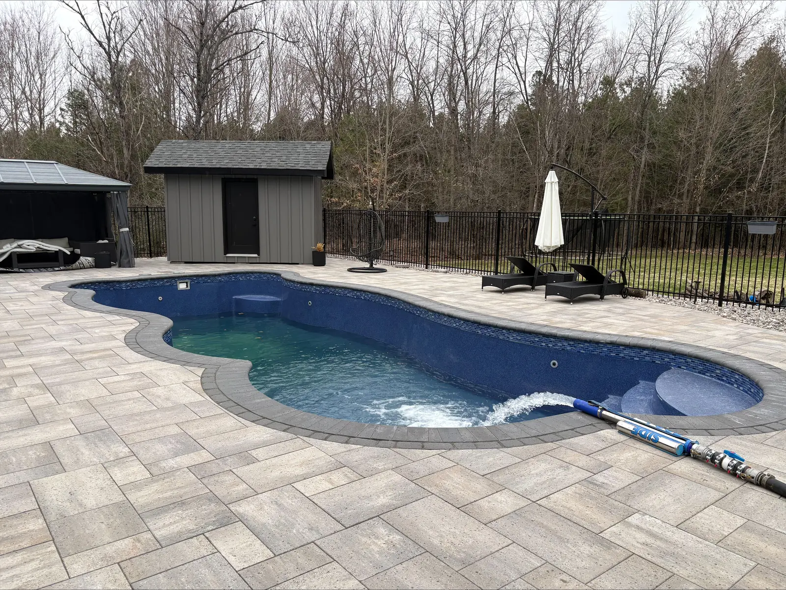 Freeform inground pool with paver patio in Ottawa being filled by Pool Side Water Services