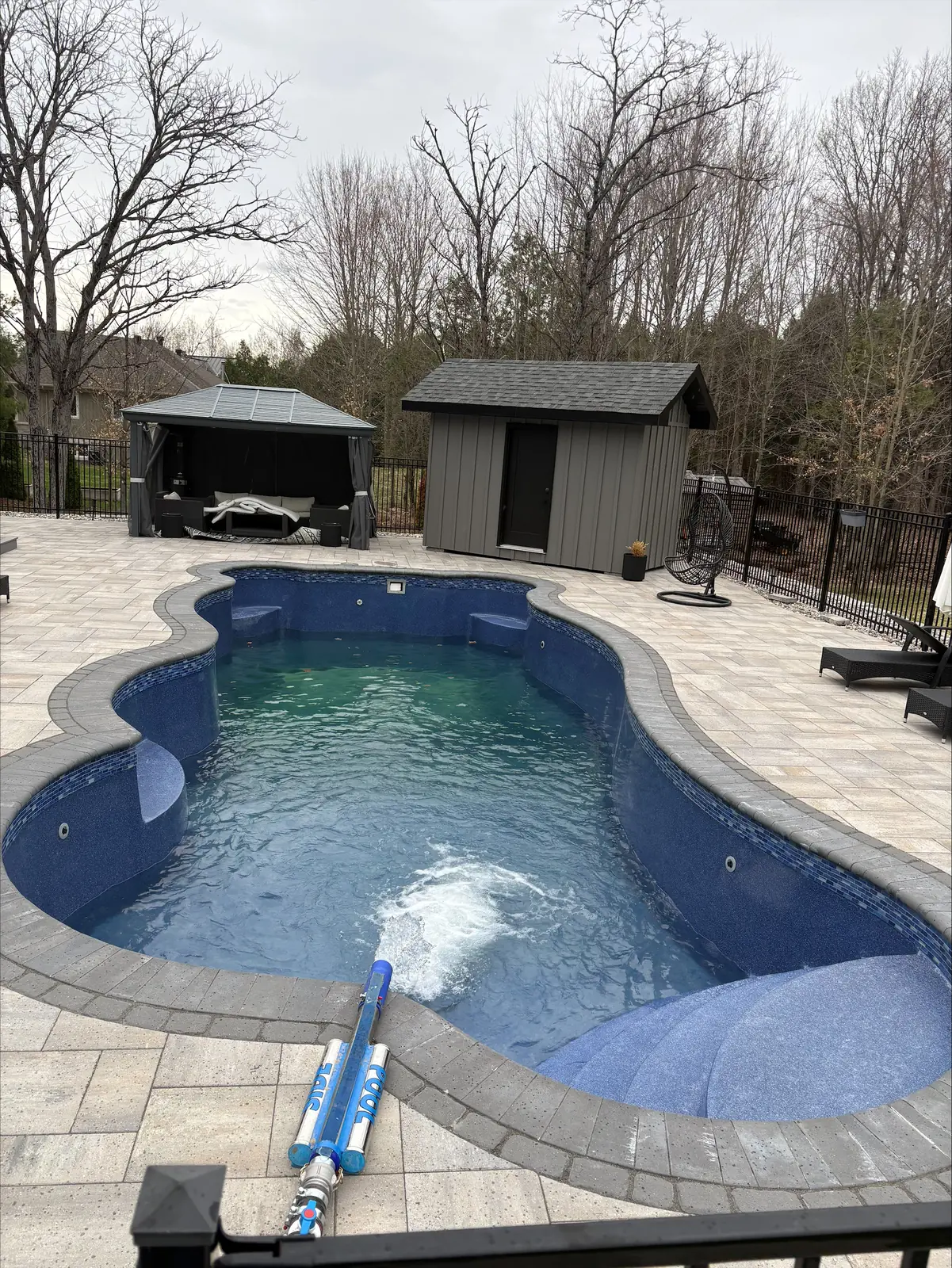 Backyard freeform pool with gazebo in Ottawa filling up during a Pool Side Water Services delivery