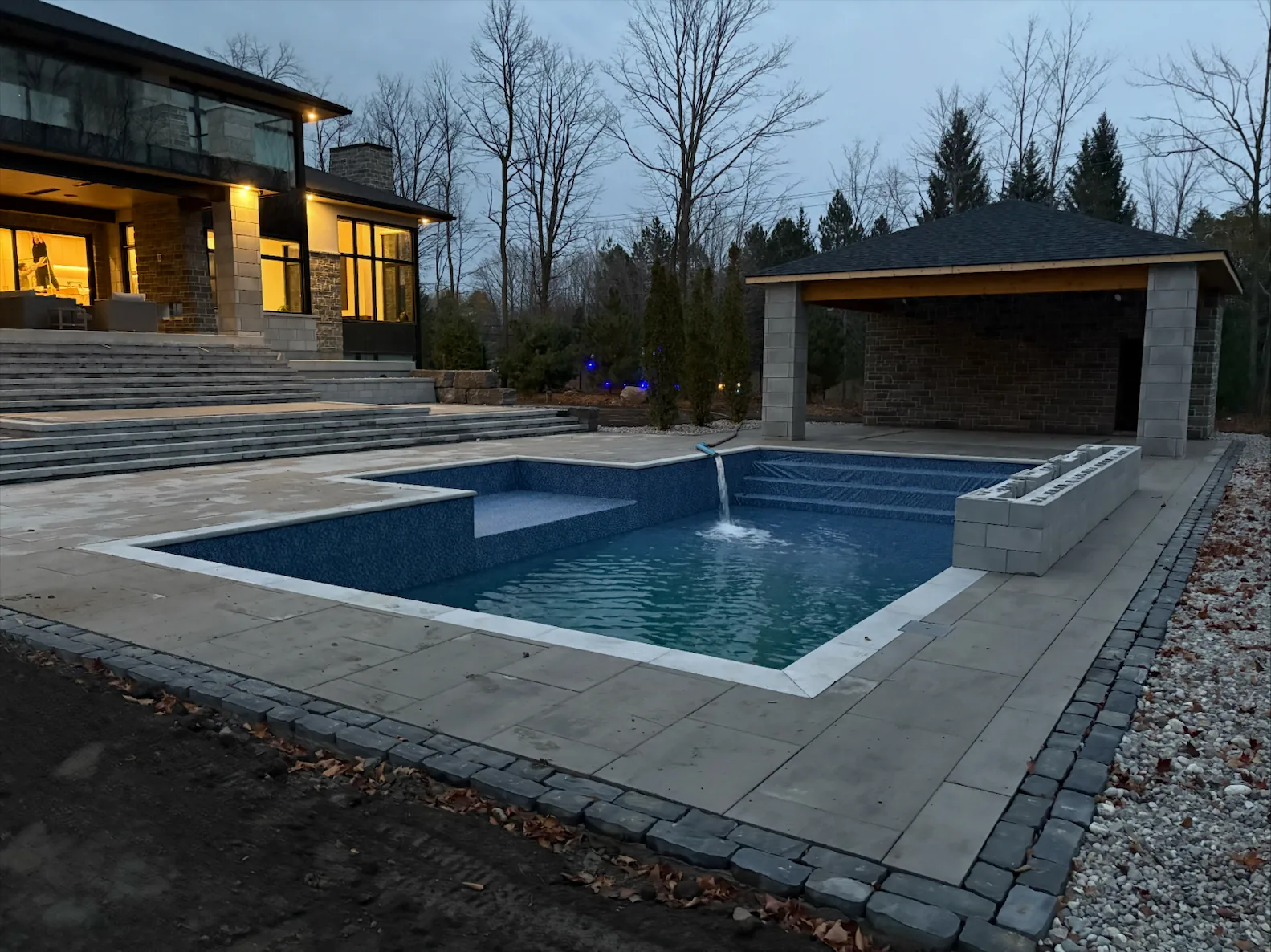 Newly built luxury backyard pool and cabana in Ottawa being filled at dusk by Pool Side Water Services